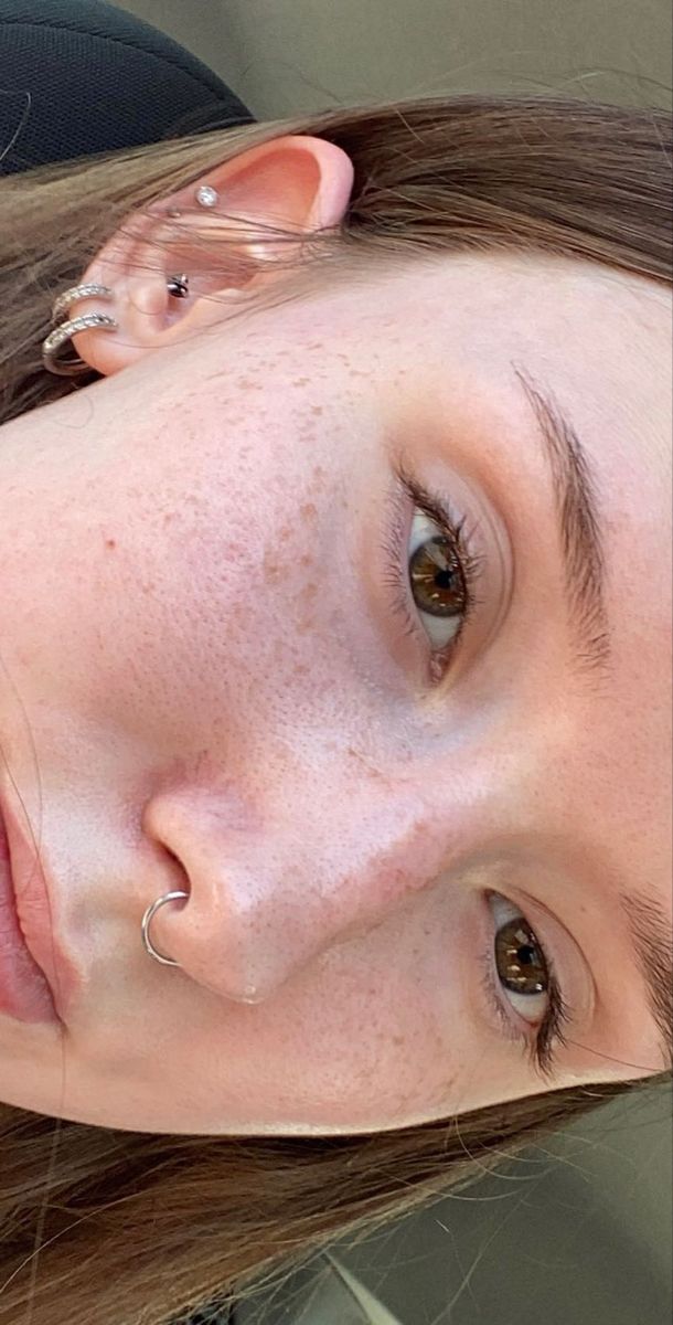 a woman with freckles and piercings on her ears