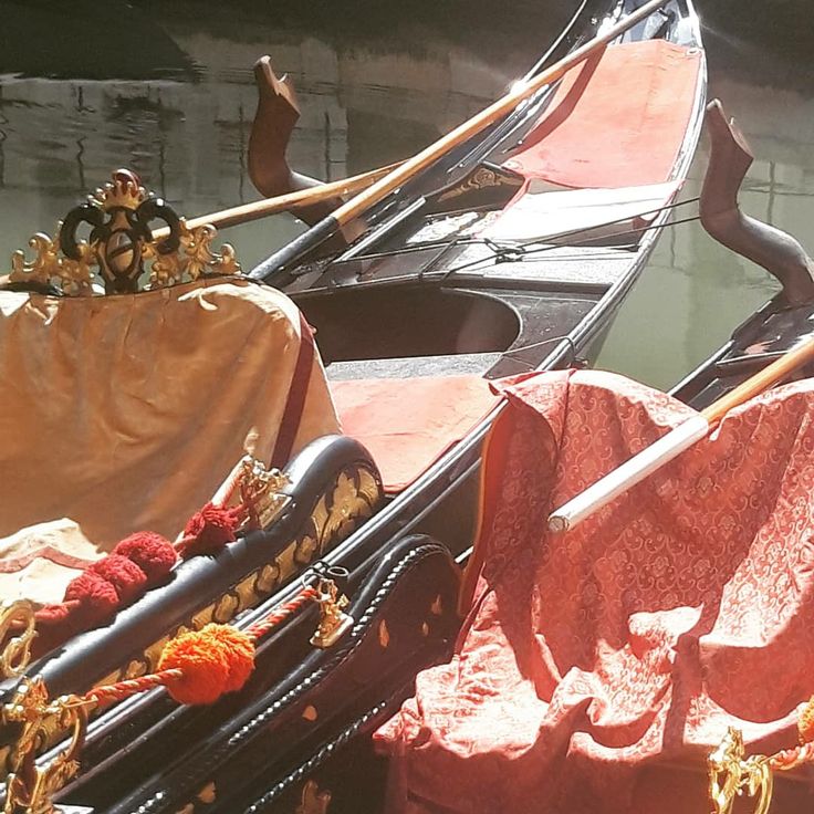 two gondolas with red cloths and gold decorations on them are docked in the water