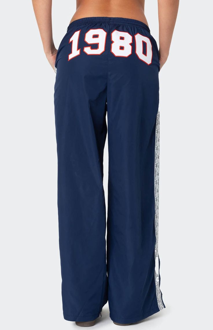 These Edikted 1980 Nylon Track Pants offer both style and comfort, making them perfect for a sporty yet fashionable look. They're ideal for any activity, ensuring you feel comfortable and confident throughout your entire day. Track pantsLace stripe detailingSlitted hemAdjustable waist tieEmbroidered graphic textPolyesterModel wears size SModel height is 5'8Item care: Machine wash at maximum 30C, wash with similar colors, do not bleach, do not tumble dry, iron at a maximum of 110C, do not dry clean. Edikted Womens 1980 Nylon Track Pants - Blue size Large Sweatpants With Words On Back, White Track Pants, Nylon Track Pants, Vintage Sweatpants, Graphic Sweatpants, Hip Hop Pants, Birthday Fits, Elastic Pants, Sweatpants Outfit