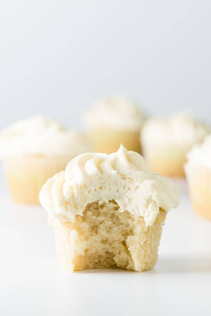 cupcakes with white frosting sitting on a table