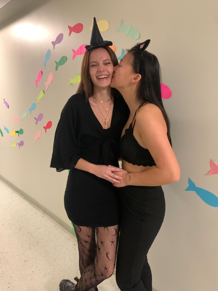 two women are kissing each other in front of a wall with fish decorations on it