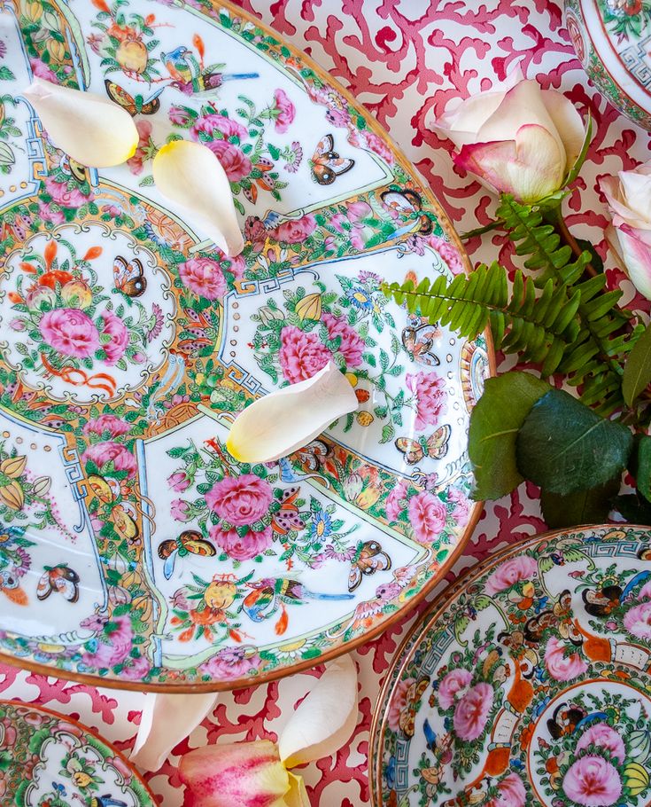 three plates with flowers on them sitting next to each other in front of a wall