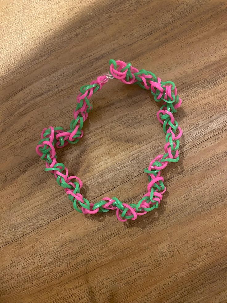 a pink and green bracelet sitting on top of a wooden table