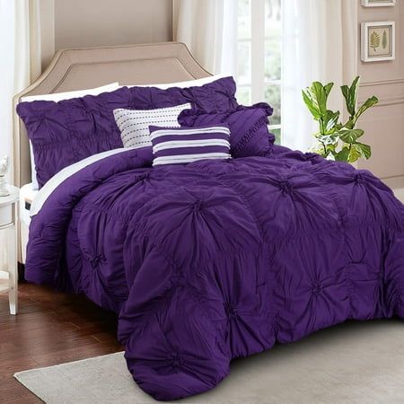 a bed with purple comforter and pillows in a room