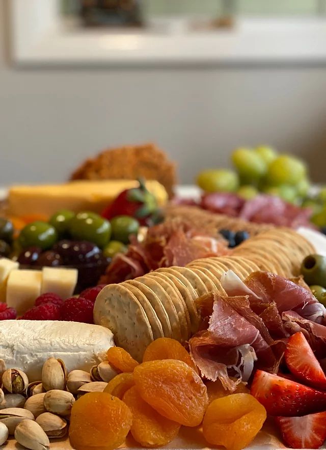 an assortment of cheeses, fruits and nuts on a plate