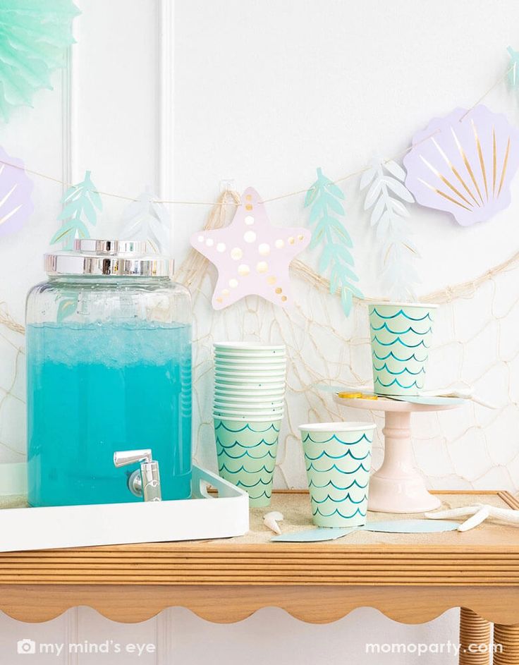 there is a shelf with cups and containers on it, along with paper garlands