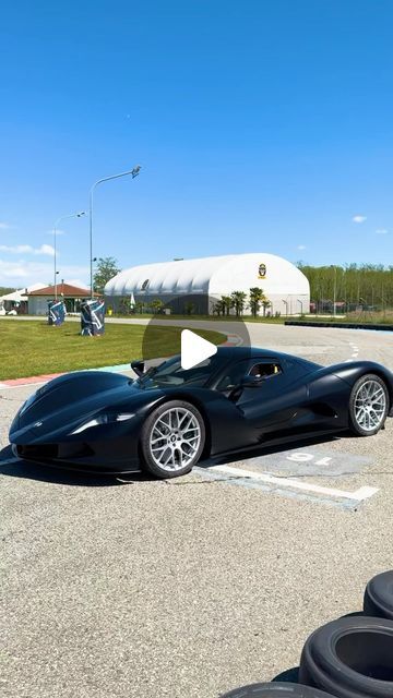 a black sports car parked in a parking lot next to some tires on the ground