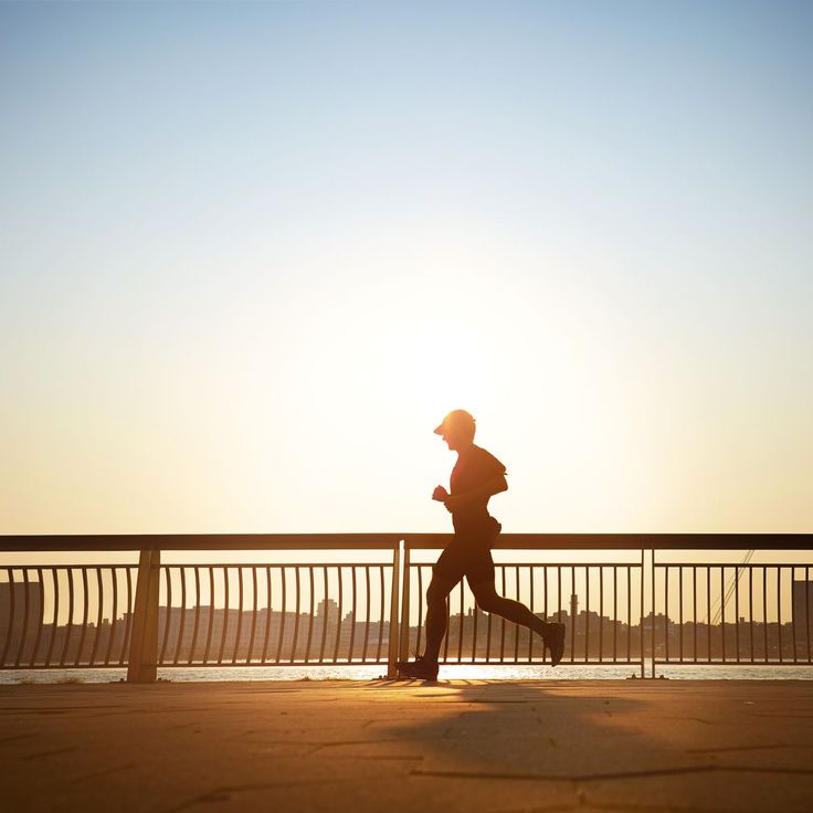 a man running across a bridge with the sun setting in the backgrounnd