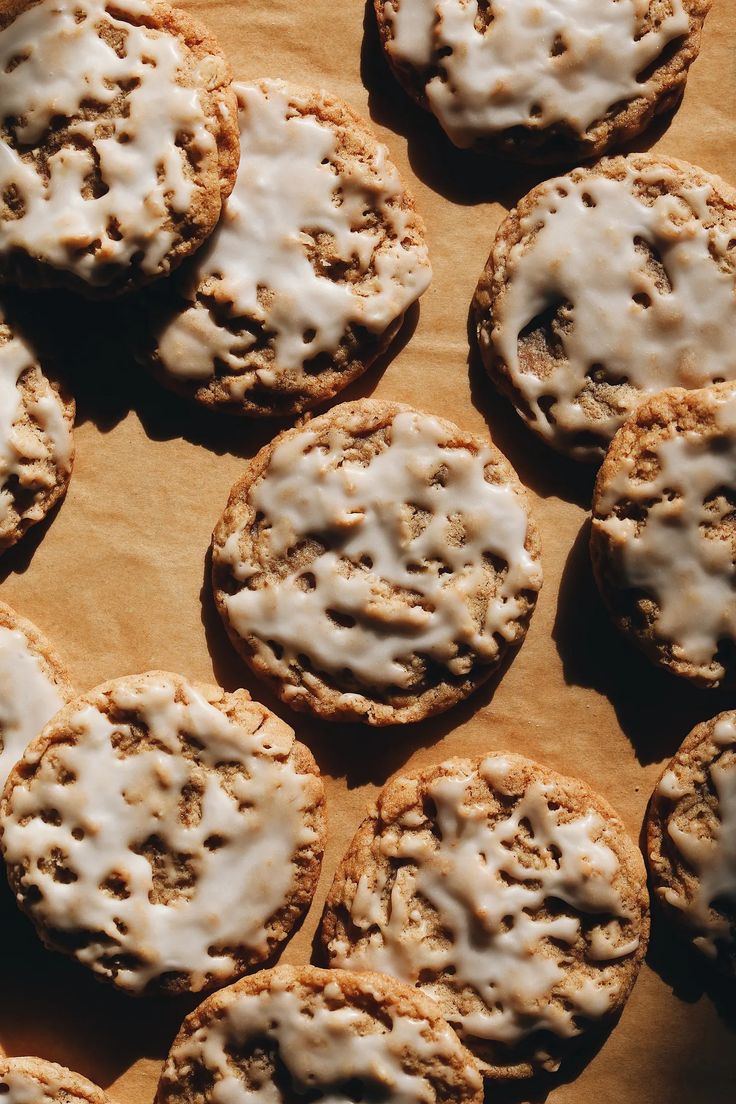 cookies with white icing are arranged on a piece of parchment paper, ready to be eaten