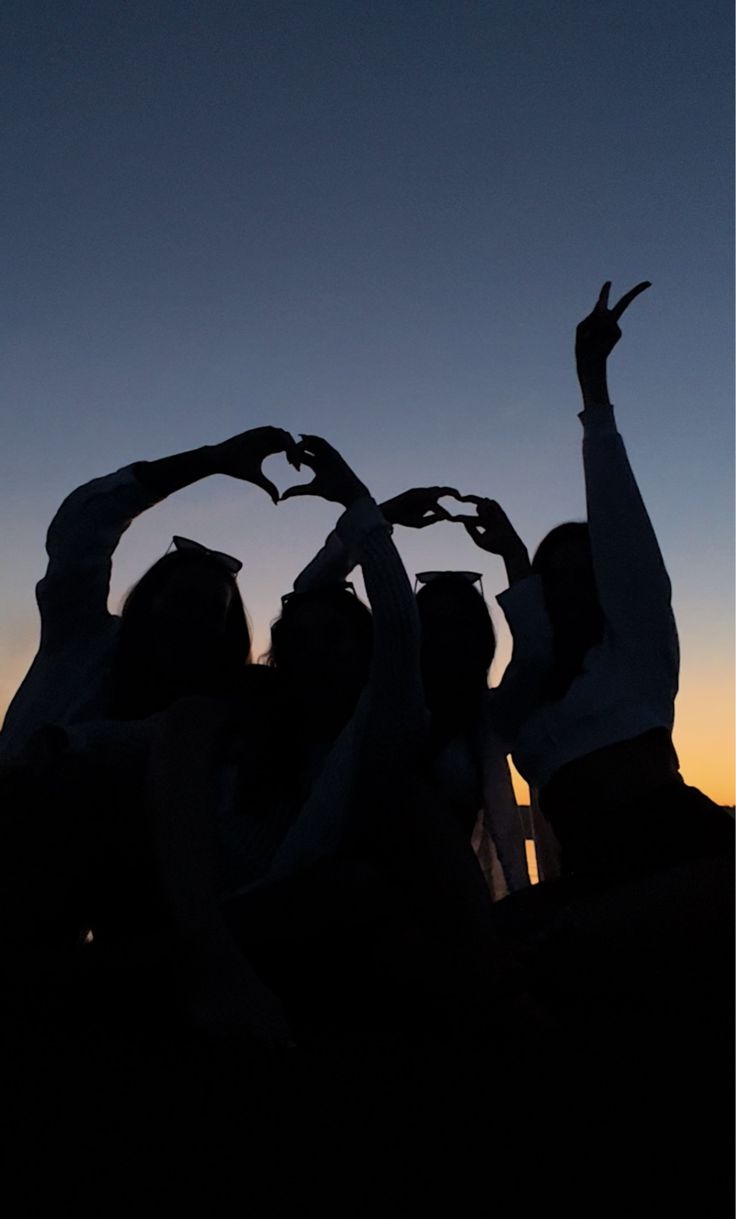 silhouettes of people making heart shapes with their hands