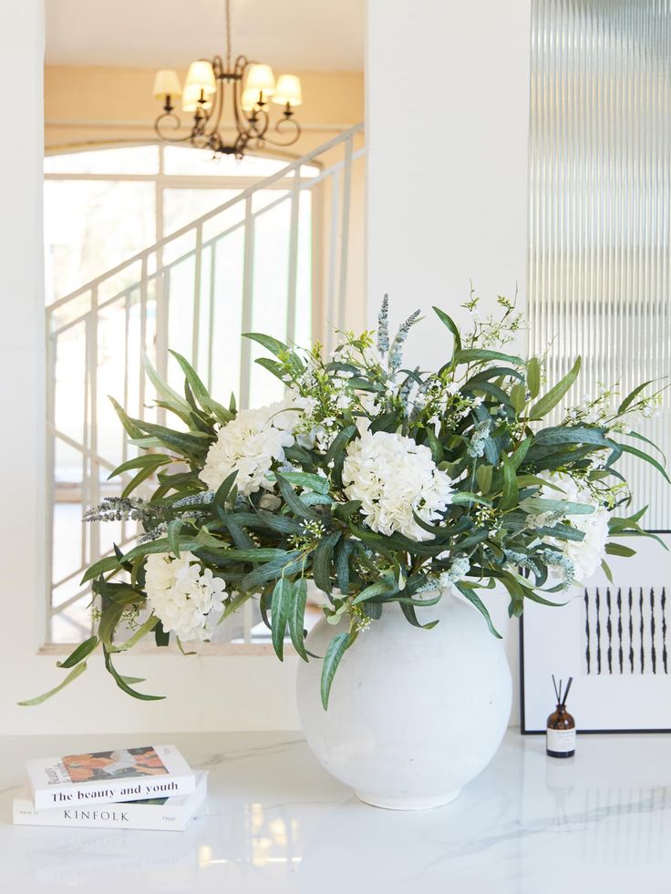 a white vase filled with flowers on top of a table