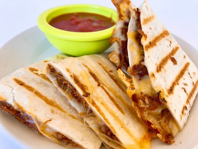 two quesadillas on a plate with a bowl of salsa