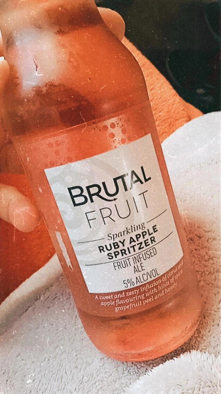 a bottle of fruit juice sitting on top of a towel next to a person's hand