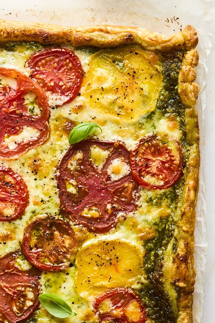 a square pizza with tomatoes, cheese and herbs on it's crusting surface