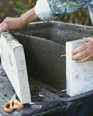 a man is working with cement in his backyard area, using scissors to cut through the concrete