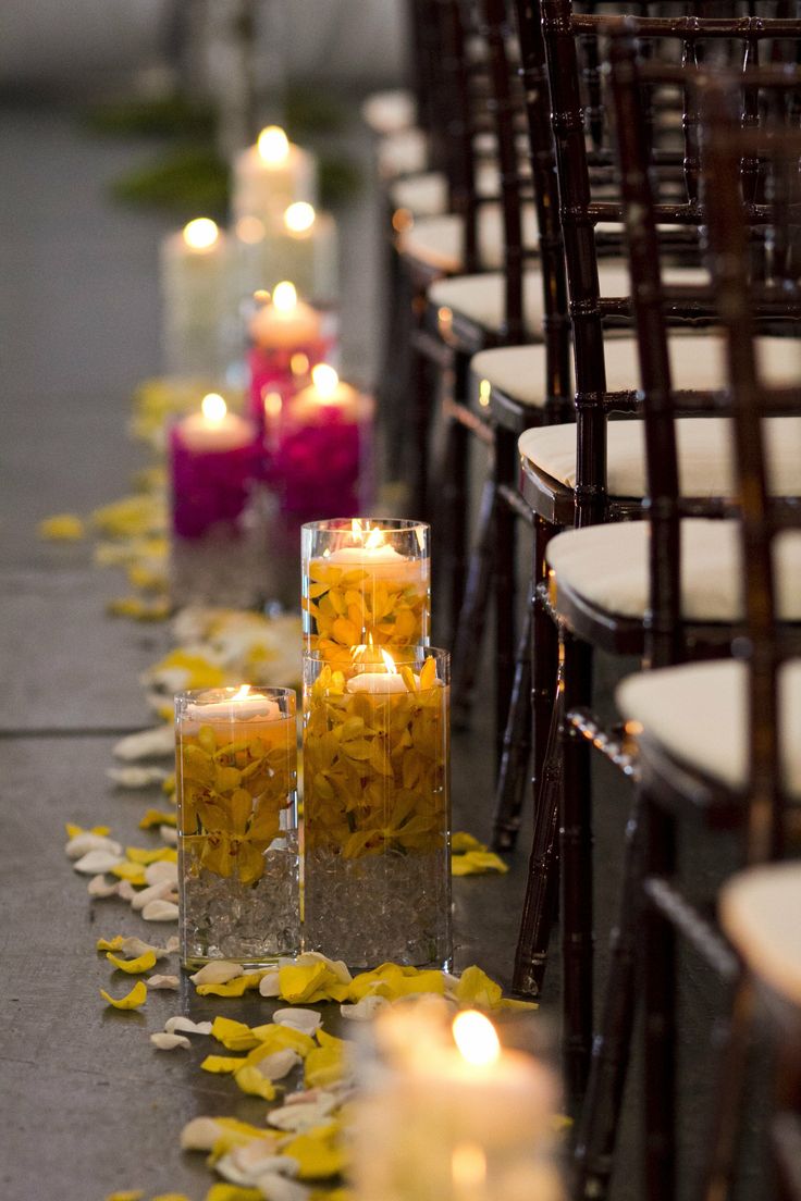 rows of chairs lined up with candles and petals on the ground in front of them