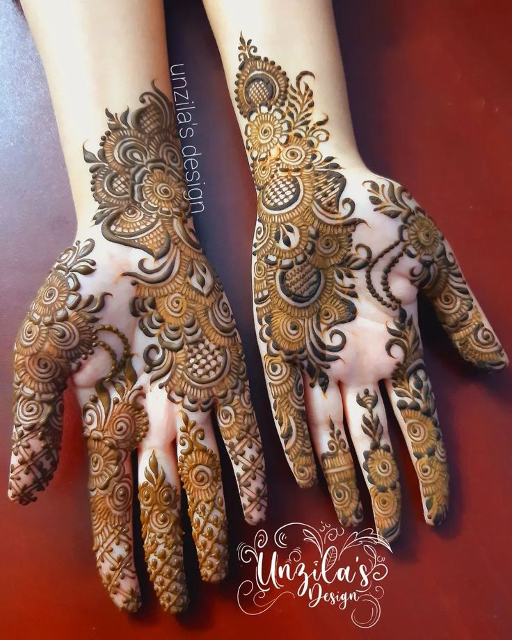 two hands with henna tattoos on them, one is showing off the intricate design