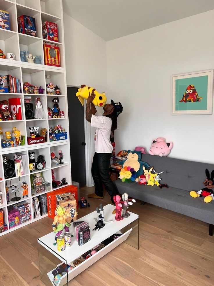 two people in a living room holding up stuffed animals