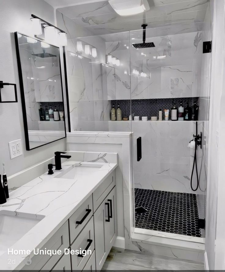 a white bathroom with marble counter tops and black accents on the shower wall, along with two sinks