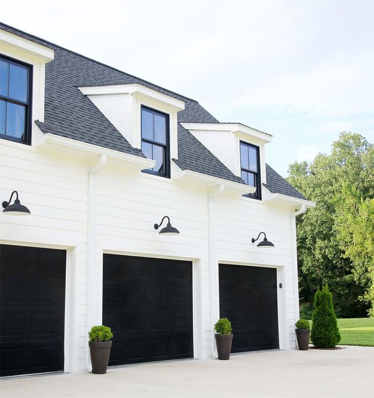 a large white house with three black garage doors