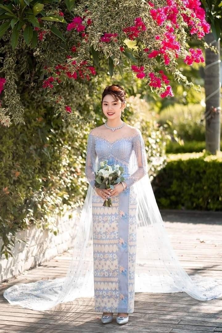 a woman in a wedding dress standing under some flowers