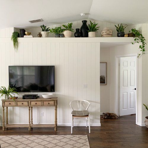 a flat screen tv sitting on top of a wooden table next to a white wall