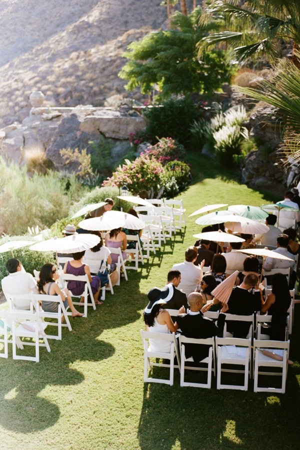 a group of people sitting on lawn chairs under umbrellas in the grass next to mountains