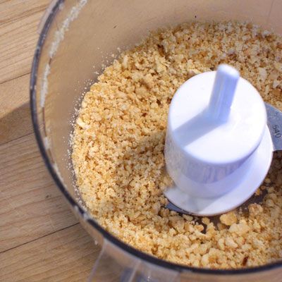 a food processor filled with brown rice on top of a wooden table next to a knife