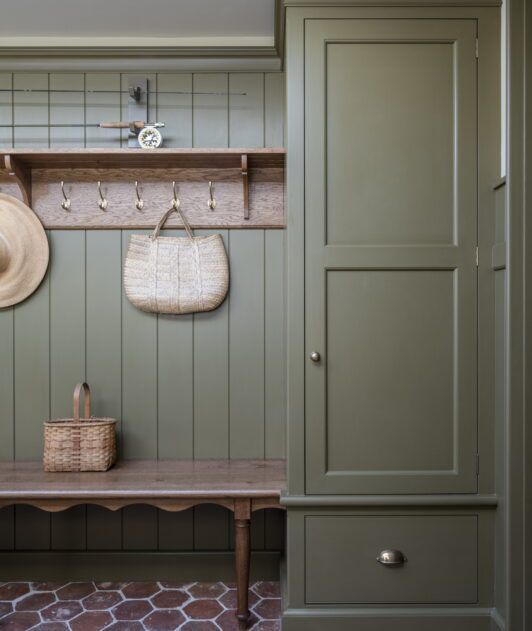 an entryway with green painted walls and wooden bench, coat rack, hat hanger, and basket