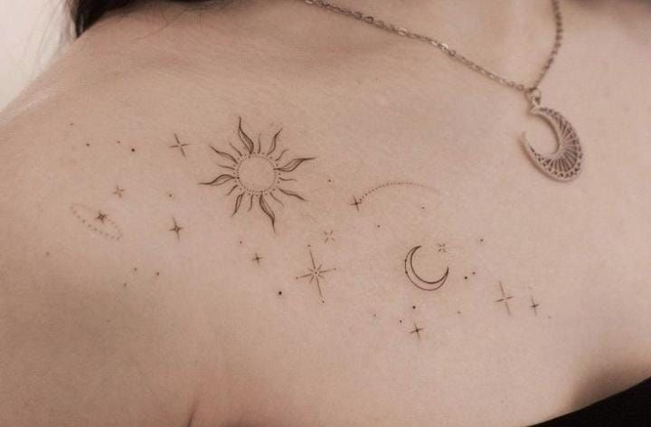 the back of a woman's shoulder with stars, moon and crescent tattoos on it