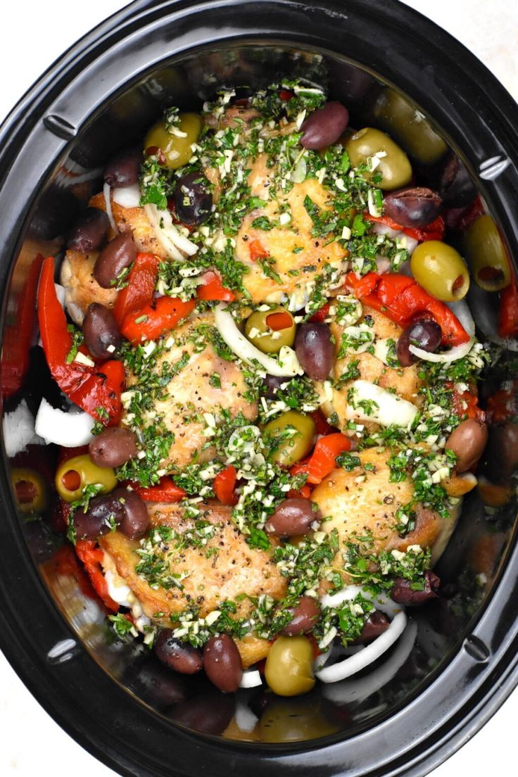 an overhead view of a crock pot filled with olives, peppers and chicken