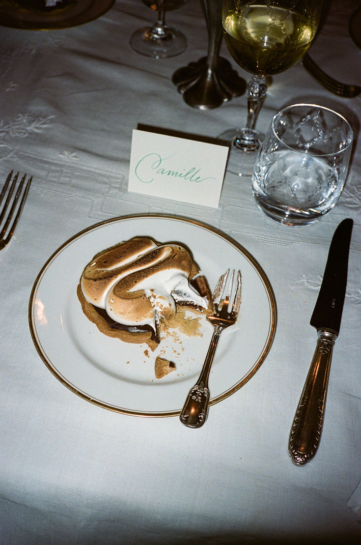 a white plate topped with food next to silverware and wine glasses on top of a table