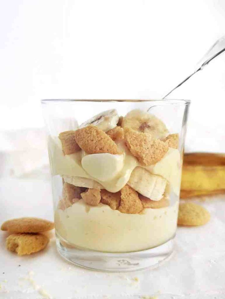 a dessert in a glass with banana slices and cream