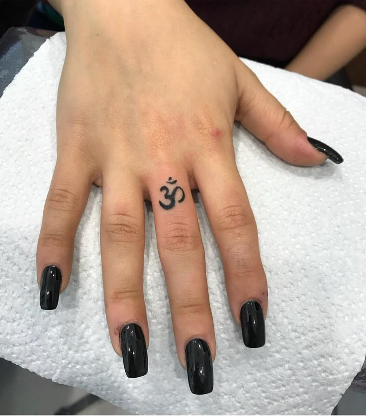 a woman's hand with a black manicure and an om symbol on it