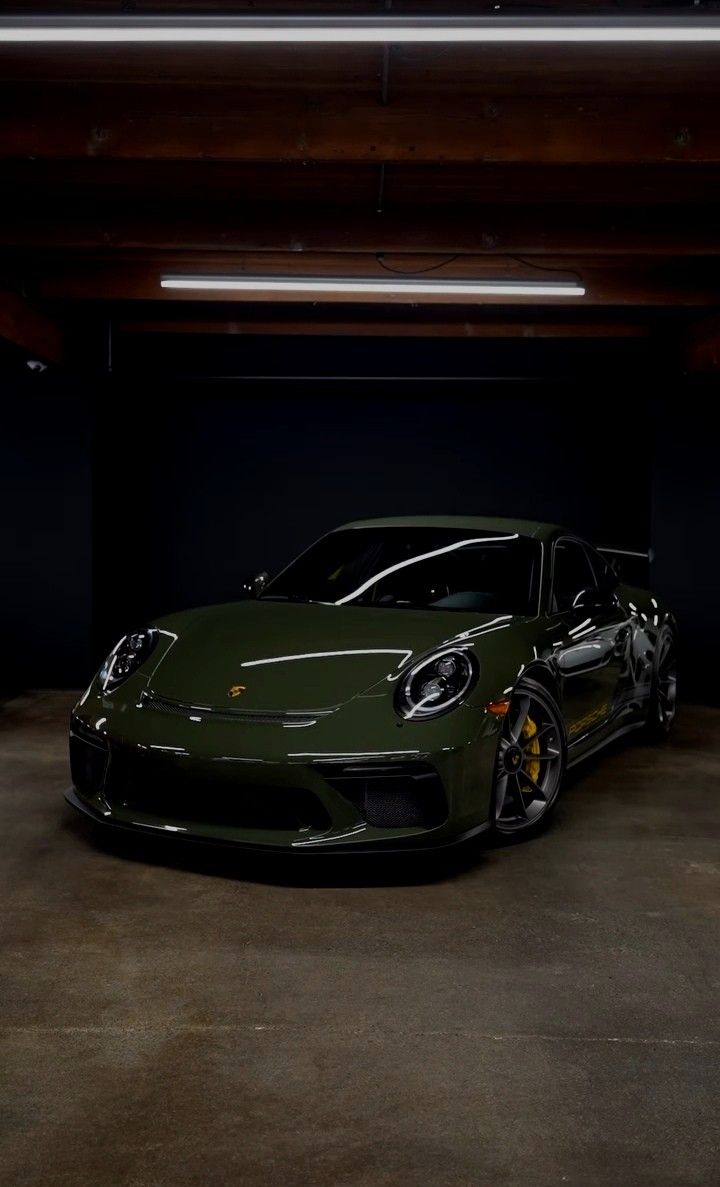 a green sports car parked in a dark parking garage with its lights on and it's door open