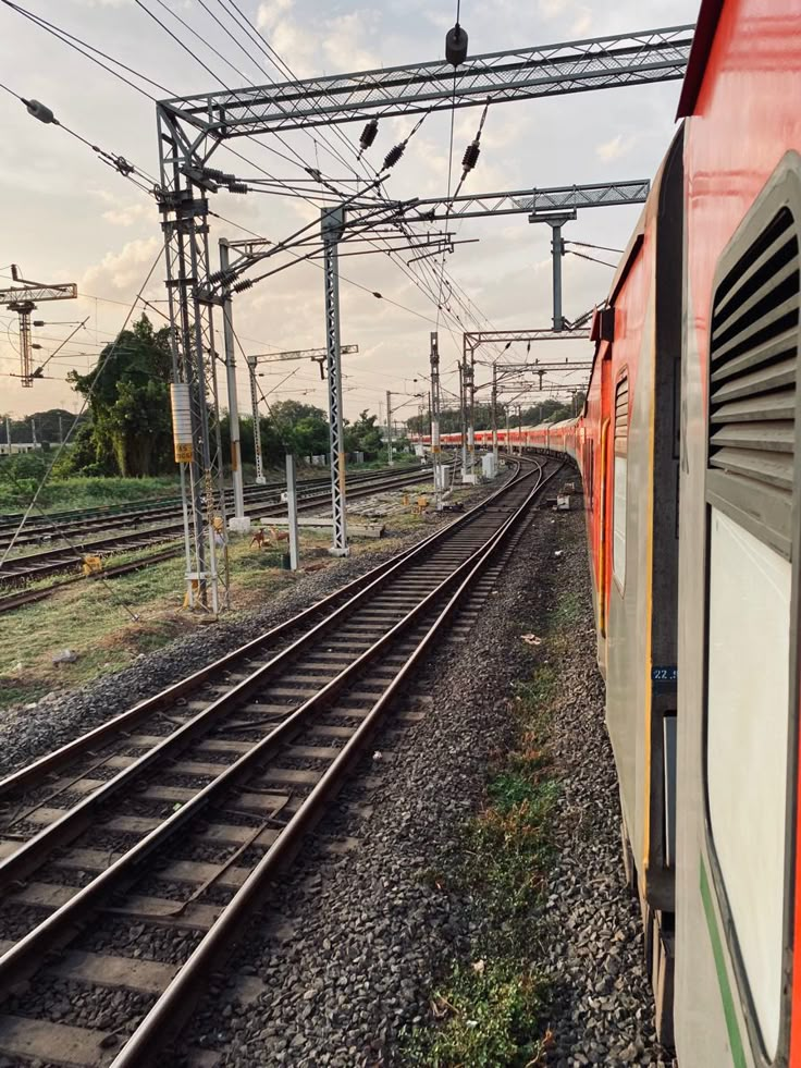 an orange train traveling down tracks next to power lines