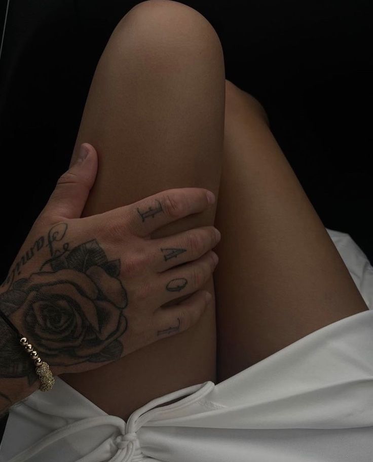 a woman with tattoos on her arm and leg is laying down in white cloths