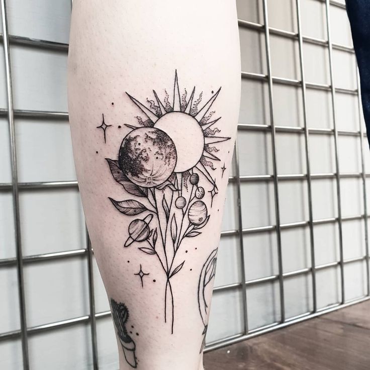 a black and white tattoo on the leg of a person with flowers in front of them