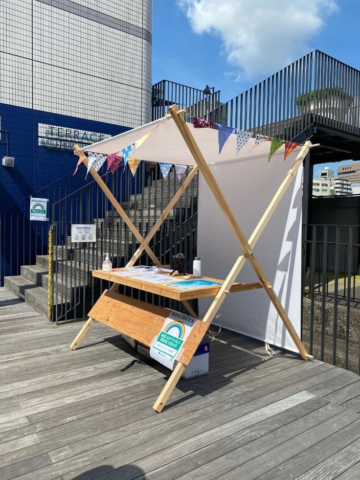 a wooden table sitting on top of a wooden deck next to a white wall and stairs