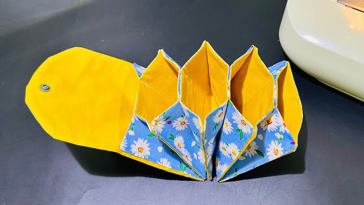 an origami flowered umbrella sitting on top of a table next to a white car