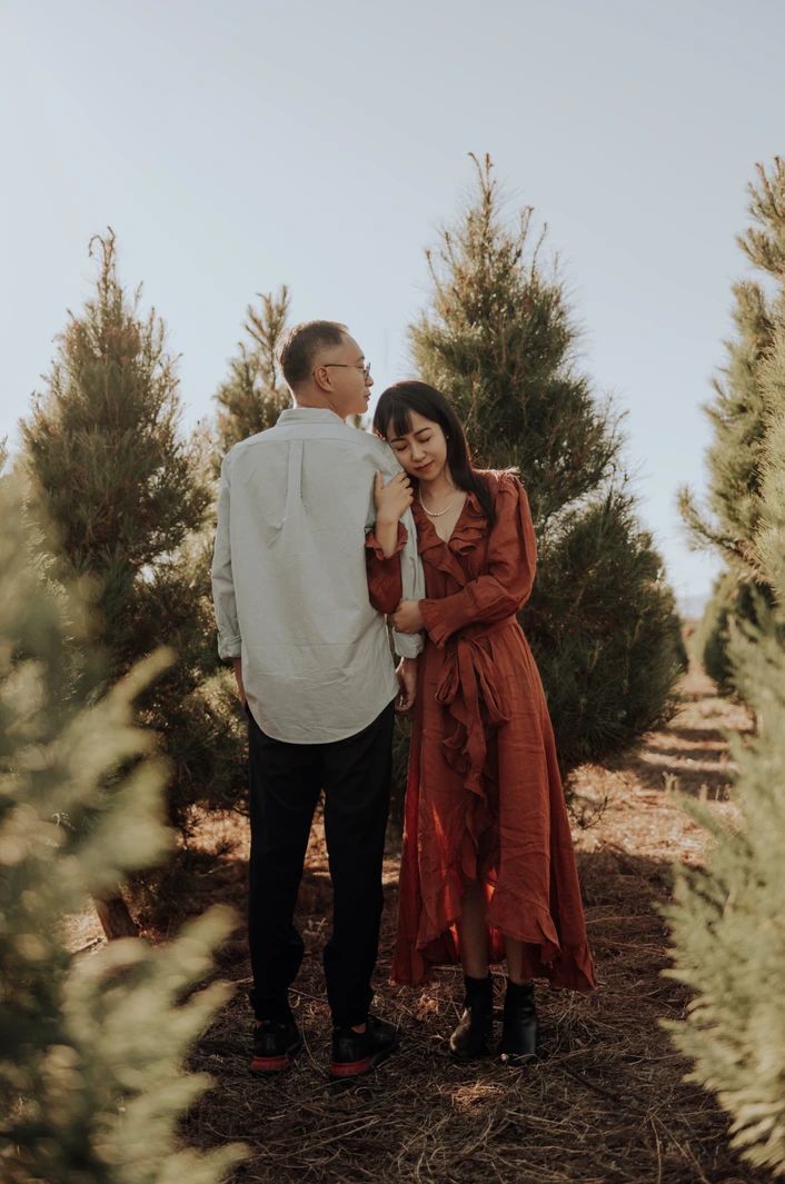 a man and woman standing next to each other in front of trees