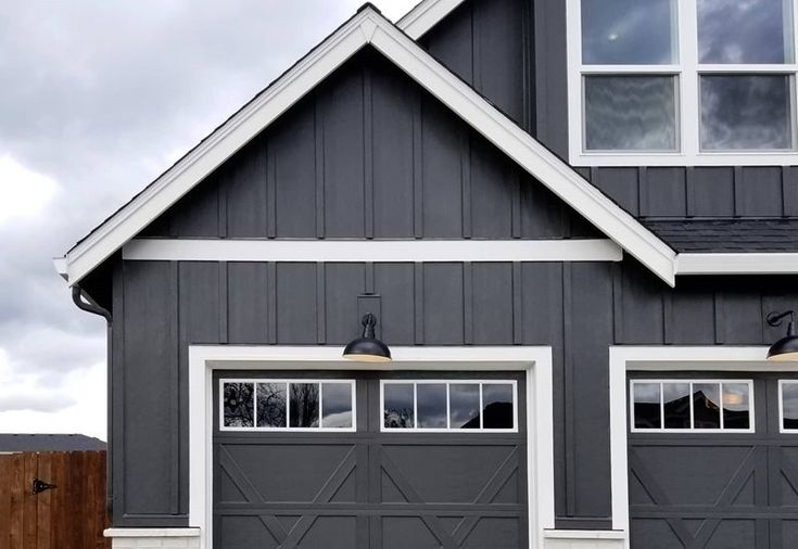 a gray house with white trim and two garage doors on the front, side and top windows