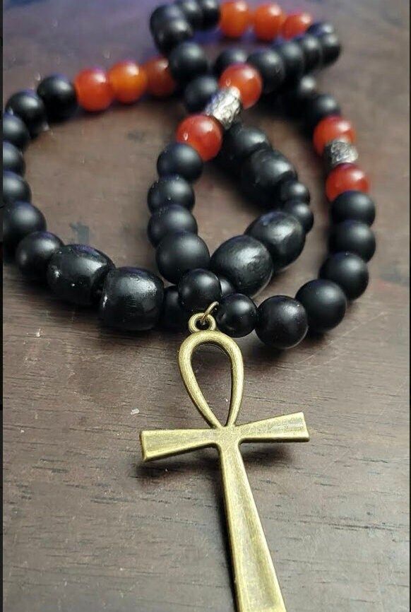 Black and Orange necklace with gold Ankh Spiritual Black Cross Beaded Necklace, Black Ankh Jewelry For Gifts, Black Amulet Style Beaded Necklaces, Black Bohemian Cross Jewelry, Bohemian Black Cross Jewelry, Adjustable Black Amulet Necklace, Black Bohemian Cross Necklace, Bohemian Black Cross Necklace, Black Ankh Spiritual Jewelry