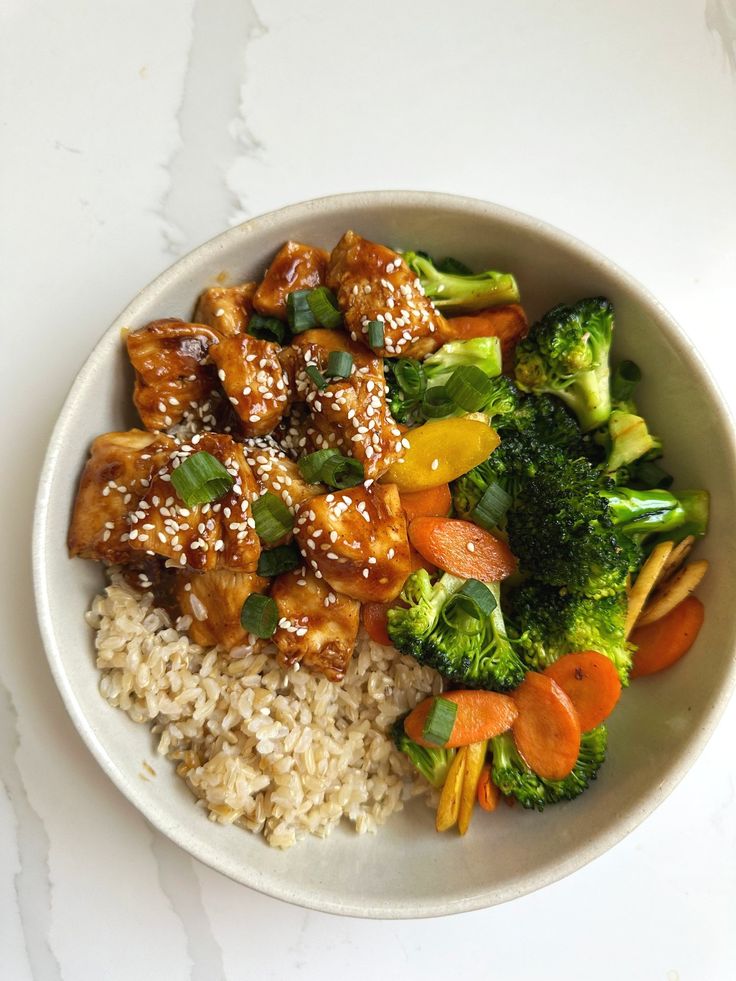 a white bowl filled with rice, broccoli and chicken