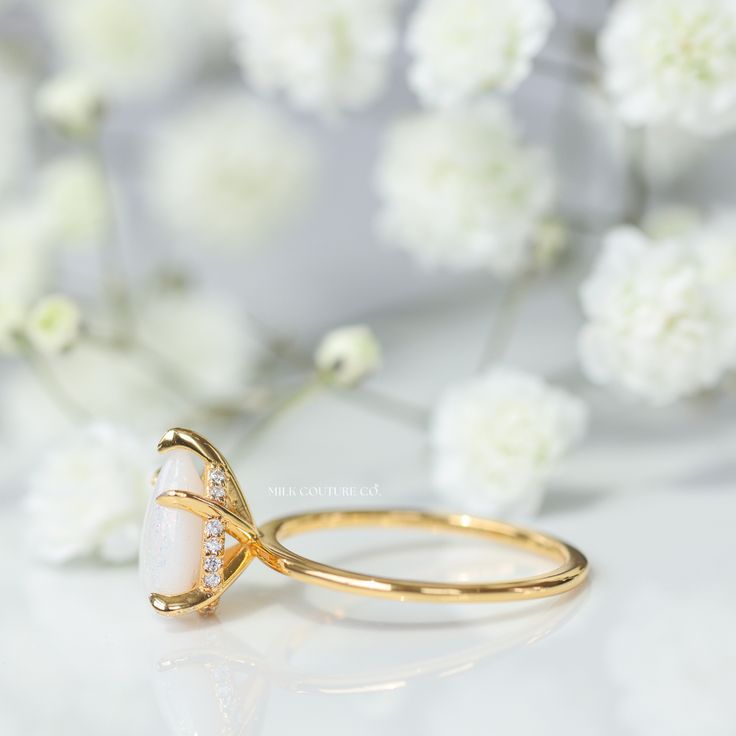 a close up of a ring on a table with white flowers in the back ground