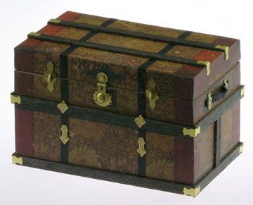 an old wooden box with gold trimmings on the top and sides, sitting on a white surface