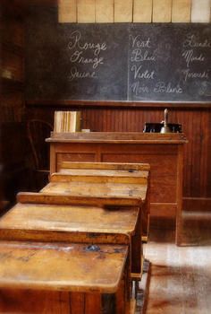 old school desks are lined up in front of a chalkboard