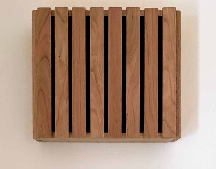 a wooden object hanging on the wall with black stripes in it's center and bottom