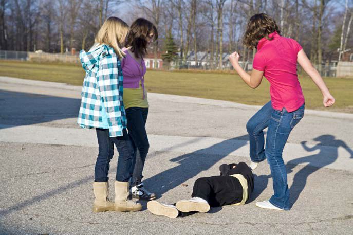 three girls are playing with a dog on the street