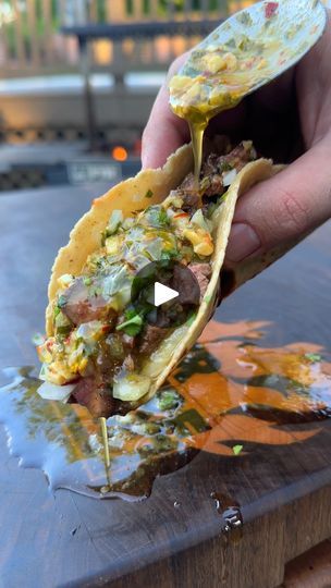 a person holding up a tortilla filled with meat and vegetables